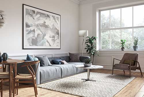 Bright contemporary living room with sofa, armchairs, patterned cushions, and modern artwork on the wall.