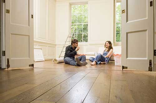 Stel zit in een opgeruimde, lege kamer na het opruimen, ontspannen en georganiseerd.