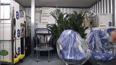 Interior of a storage unit containing office furniture, including desks and chairs.